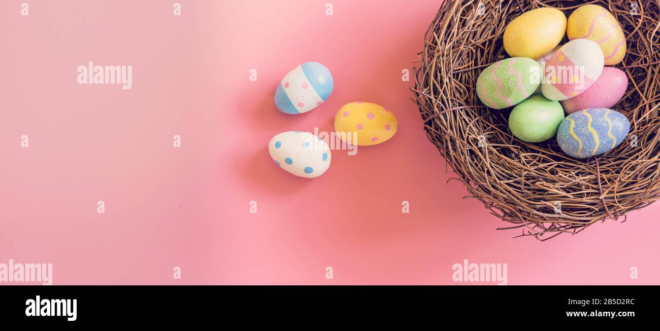 Farbenfrohes osterei und Nestchen auf pastellfarbenem Hintergrund mit Kopierraum Stockfoto