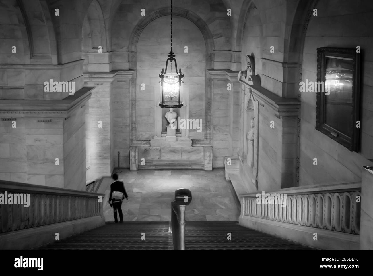 New York Public Library (NYPL) Treppe mit bewegter Person, die das Gebäude über die Treppe in Schwarzweiß verlässt. Stockfoto