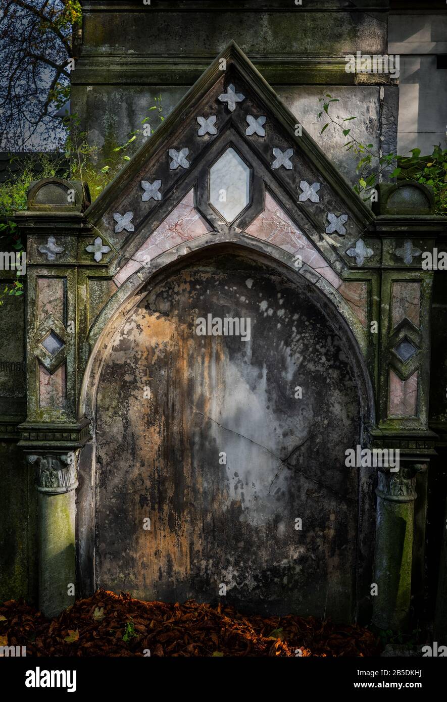 Gealtertes Grab in alter Nekropole, bogenförmige Nische mit dreieckigem, oben düsterem Gebilde, historischer Friedhof in Warschau, Polen Stockfoto
