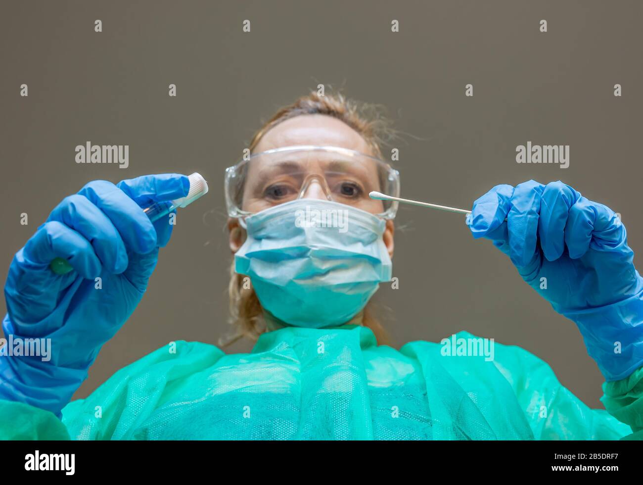 Eine blonde weiße Frau, die als Labortechnikerin arbeitet, führt einen Tupfer durch, um auf eine mögliche Coronavirus Covid-19-Infektion zu prüfen Stockfoto