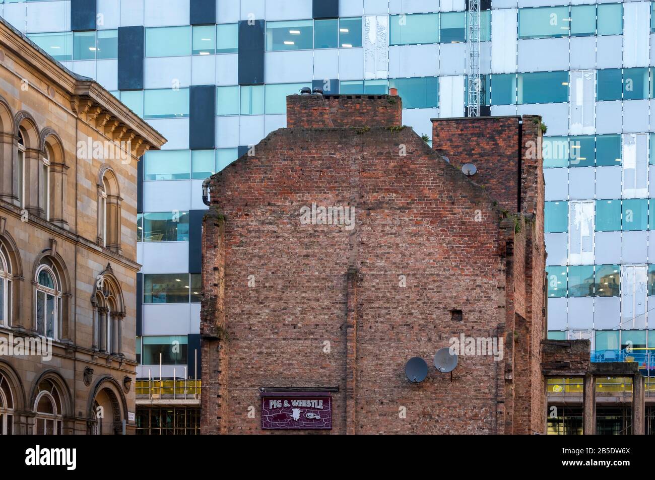 Die Rückseite des alten Gebäudes, in dem sich das Pub "Pig & Whistle" befindet, das auf die Vorderseite eines modernen Gebäudes im Stadtzentrum von Liverpool blickt Stockfoto