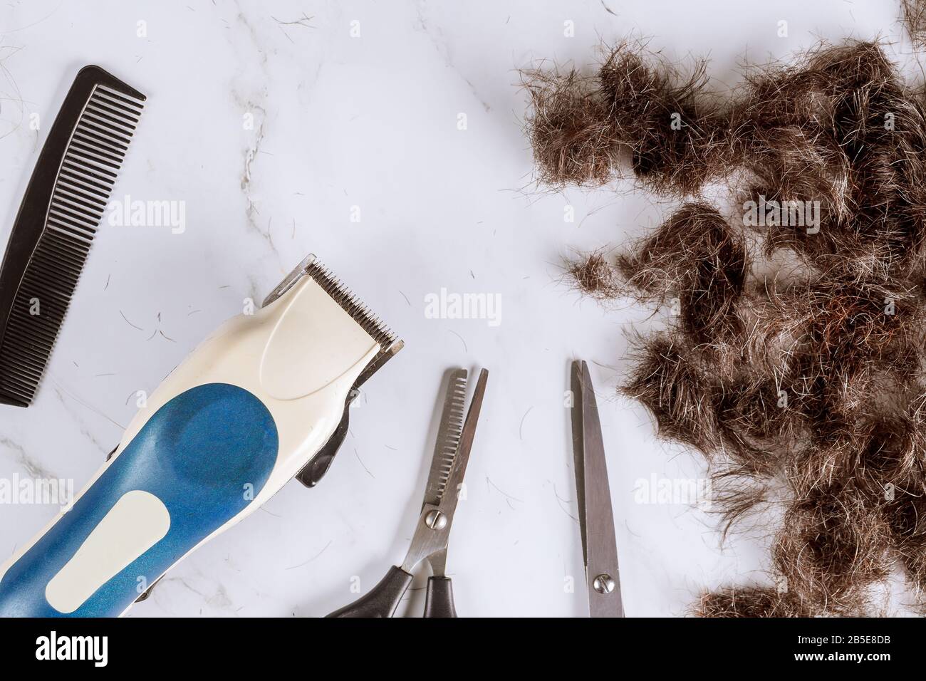 Haufen von geschnittenen Haaren und elektrischen Haarschneidern einige Clipper auf einer Schere mit Kammhaar Stockfoto