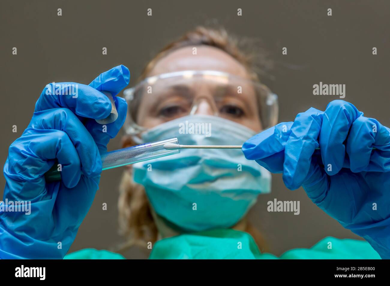 Eine blonde weiße Frau, die als Labortechnikerin arbeitet, führt einen Tupfer durch, um auf eine mögliche Coronavirus Covid-19-Infektion zu prüfen Stockfoto