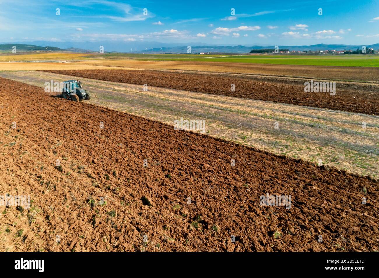 Luftdrohne schoss von einem Bauern in Traktorseeding und säte landwirtschaftliche Nutzpflanzen auf dem Feld auf den fruchtbaren Bauernfeldern von Kilkis in Nordgriechenland Stockfoto