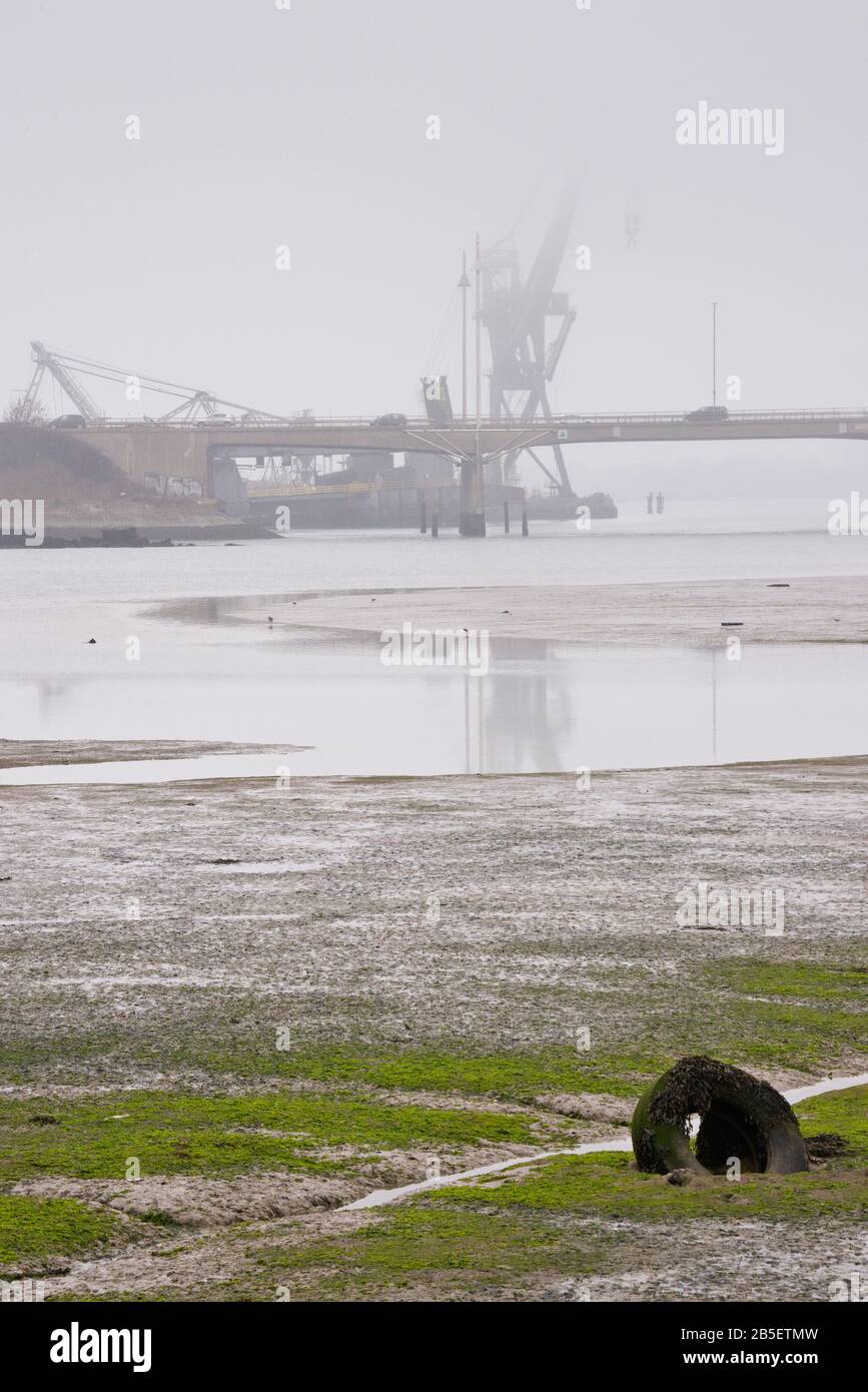 Blick über Den Ports Creek vom Alexandra Park, Portsmouth, Hampshire, England, Blick auf Pounds Yard, Tipner, mit einem Kran, der in einer niedrigen Wolke gehüllt ist. Stockfoto