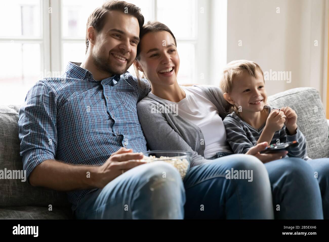 Freudiges Familienpaar kuschelig Sohn, Fernsehsendung ansehen. Stockfoto