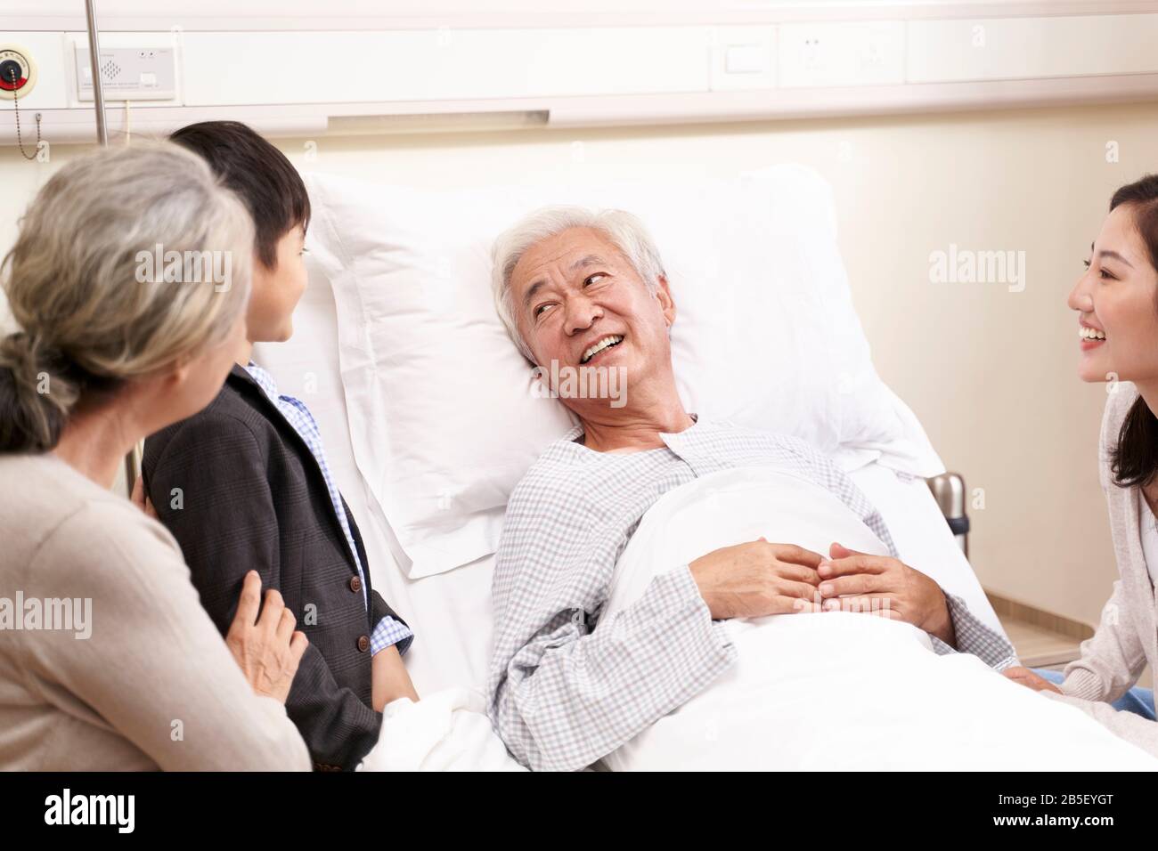 Asiatische Familie mit Kind, die Großeltern im Krankenhaus besucht Stockfoto