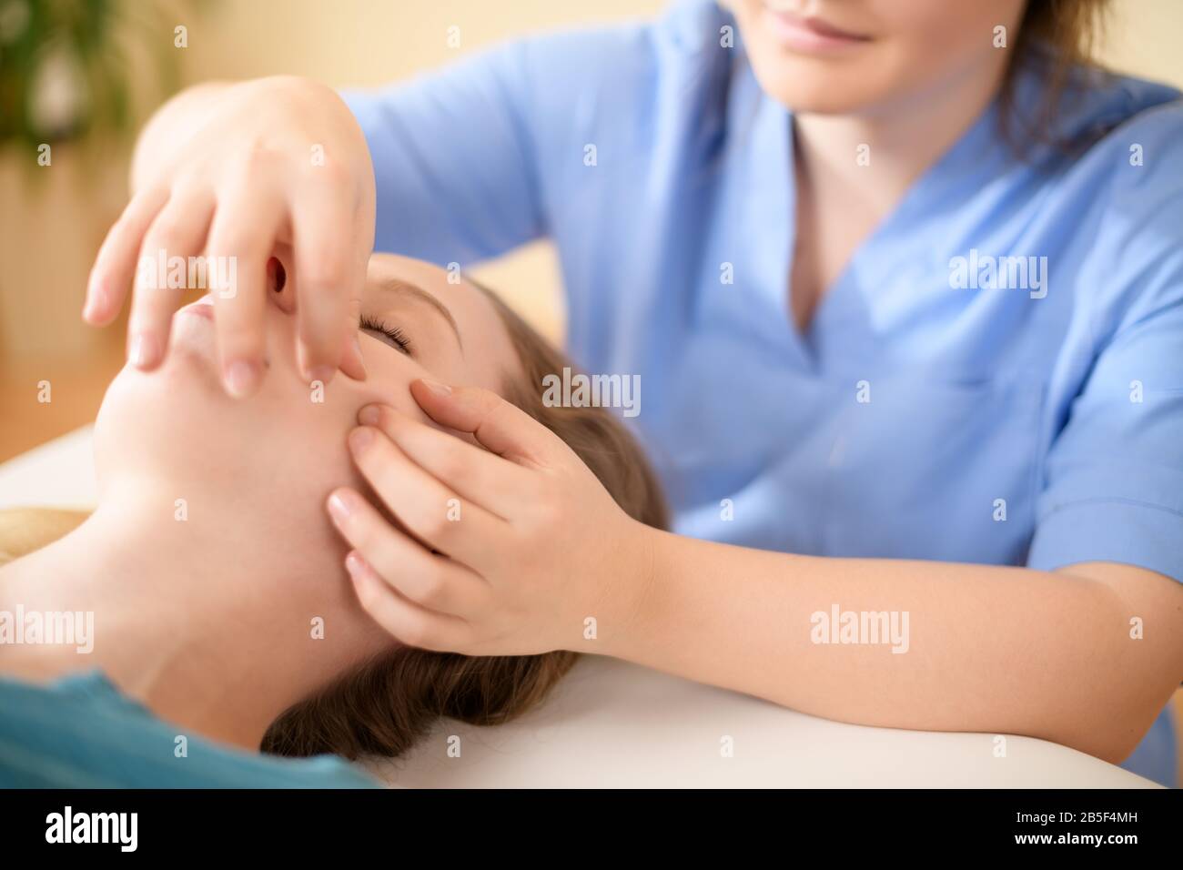 Schöne junge kaukasische Frau mit Gesichtsmassage im Spa-Salon. Entspannende Frau mit Gesichtsmassage im Spa. Stockfoto