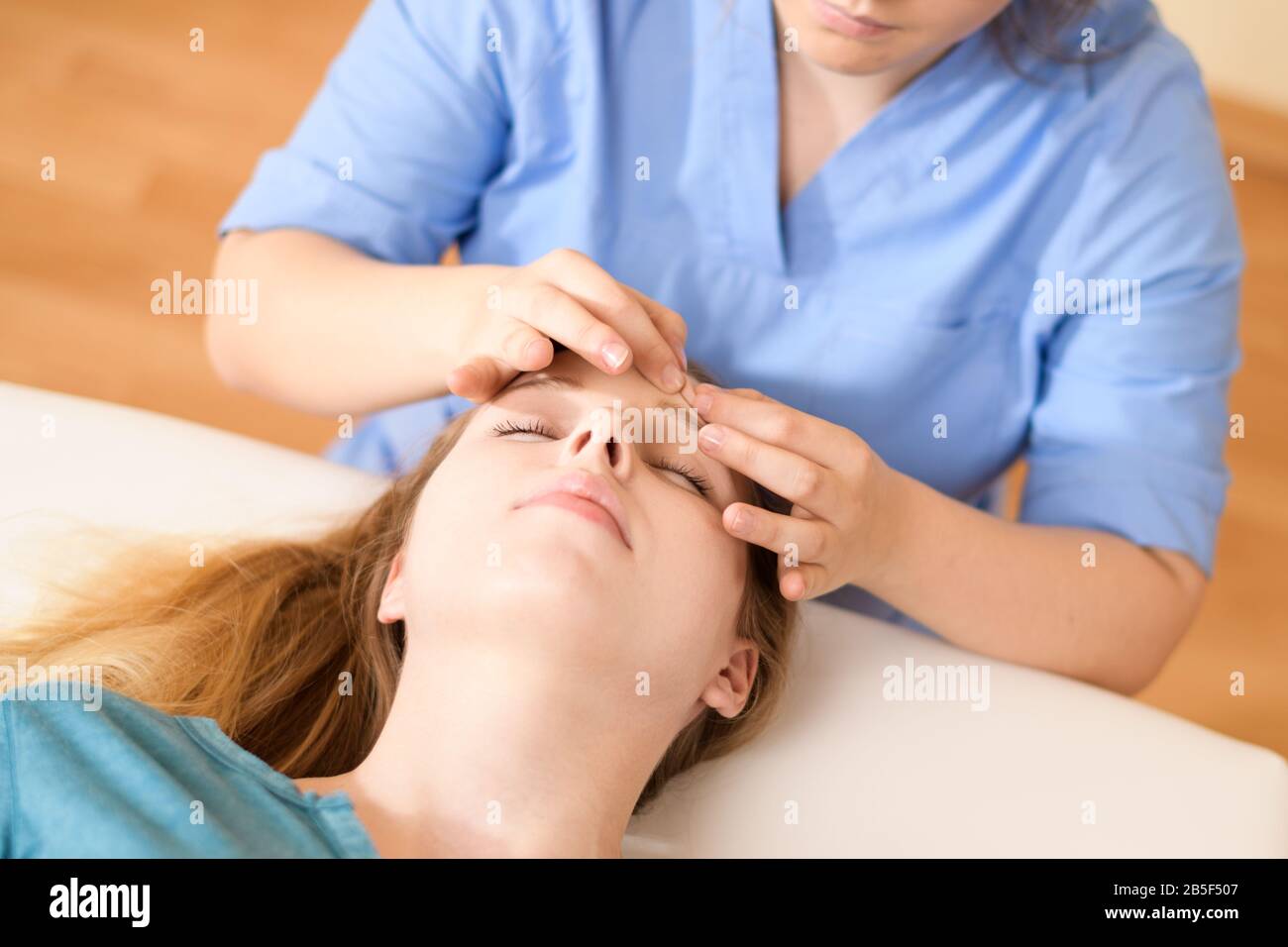 Schöne junge kaukasische Frau mit Gesichtsmassage im Spa-Salon. Entspannende Frau mit Gesichtsmassage im Spa. Stockfoto