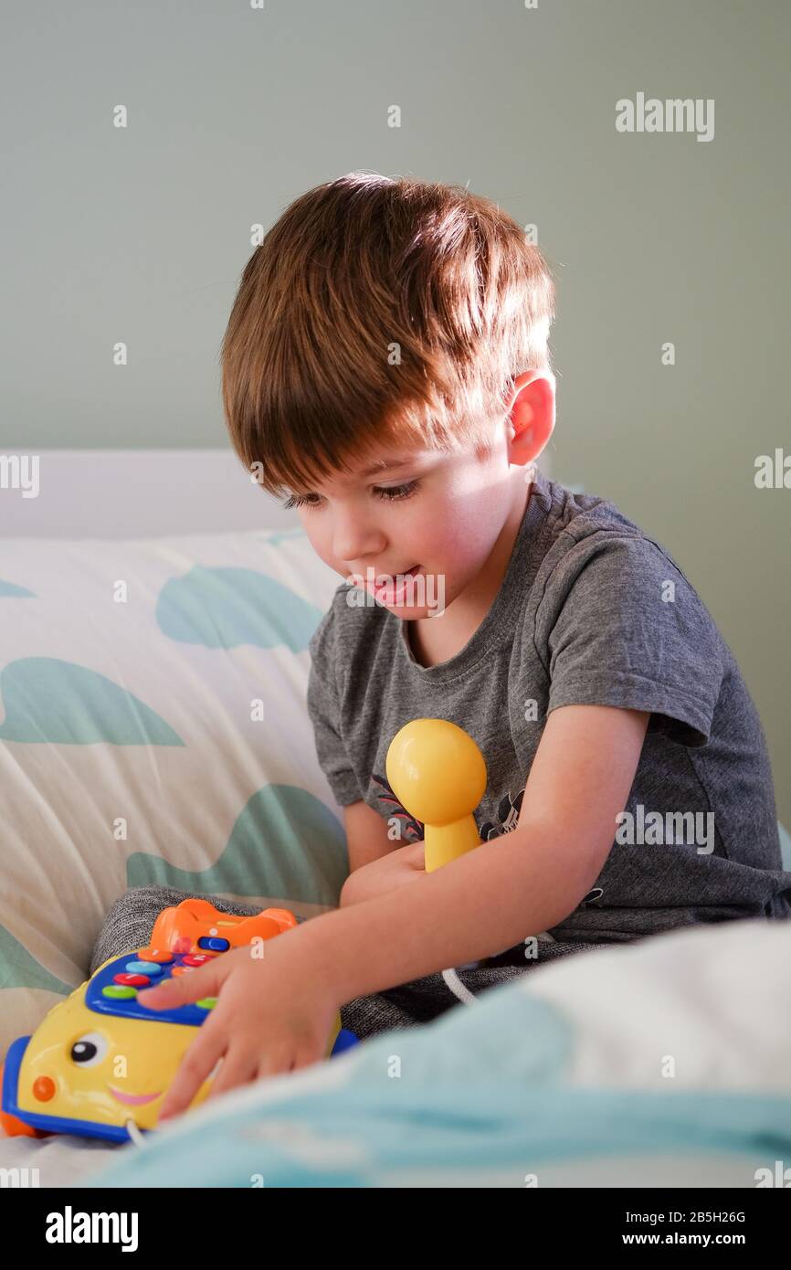 Kleiner Junge im Alter von 3 Jahren, der auf einem gelben Telefonspielzeug aus Kunststoff spielt Stockfoto