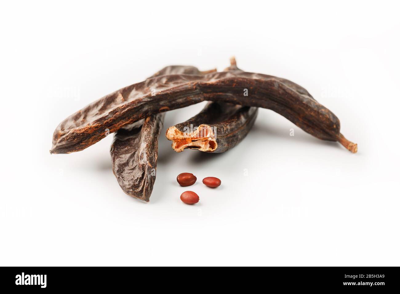 Karob-Karob-Früchte und Samen auf weißem Hintergrund. Isolieren. Biobohnen, eine gesunde Alternative zum Kakao. Stockfoto