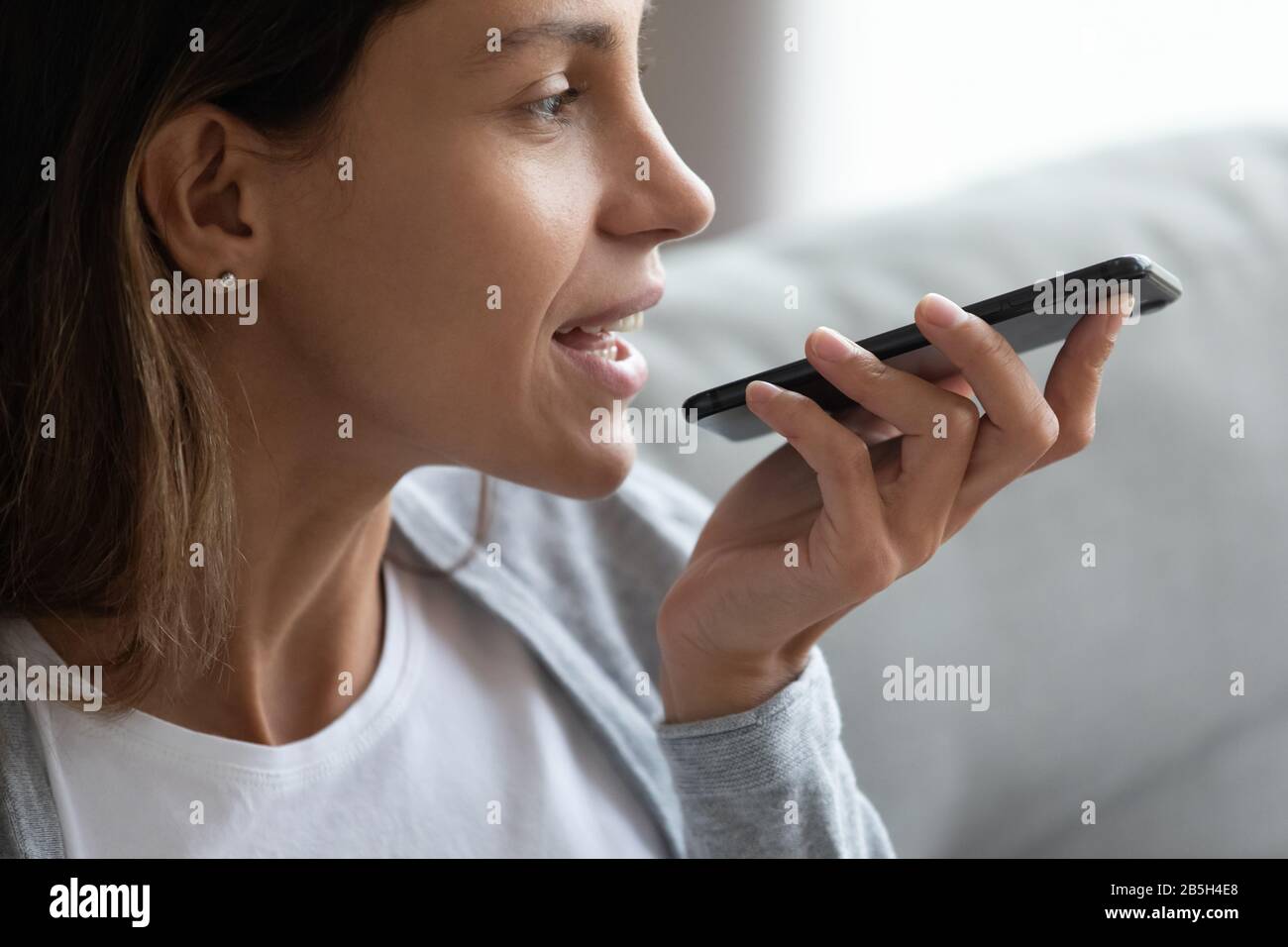 Kaukasische Frau mit Handy und digitalem Sprachassistenten Stockfoto