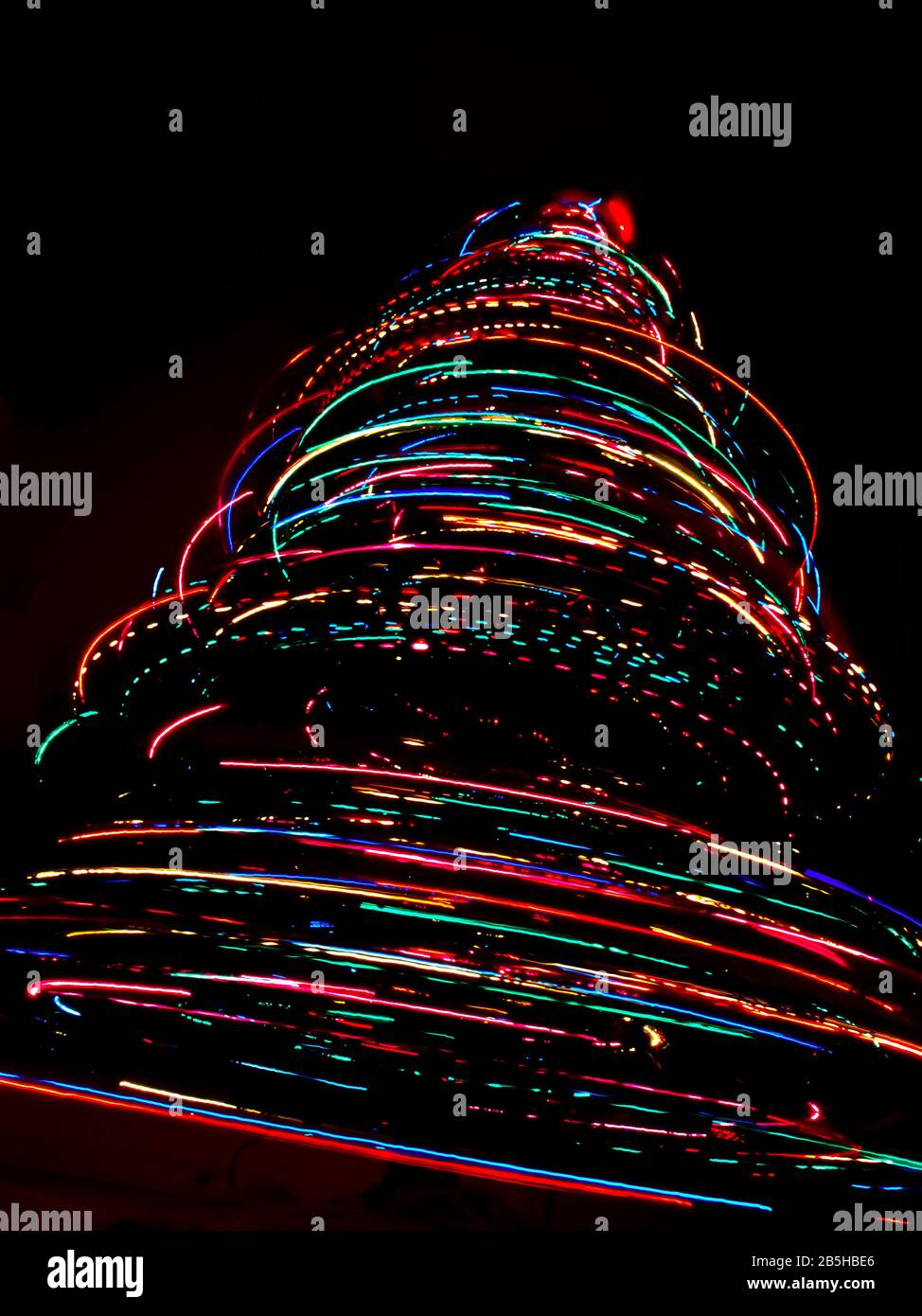 Ein abstrakter Lichtwirbel, der durch eine lange Belichtung eines rotierenden Weihnachtsbaums mit farbigen Lichtern entsteht. Stockfoto