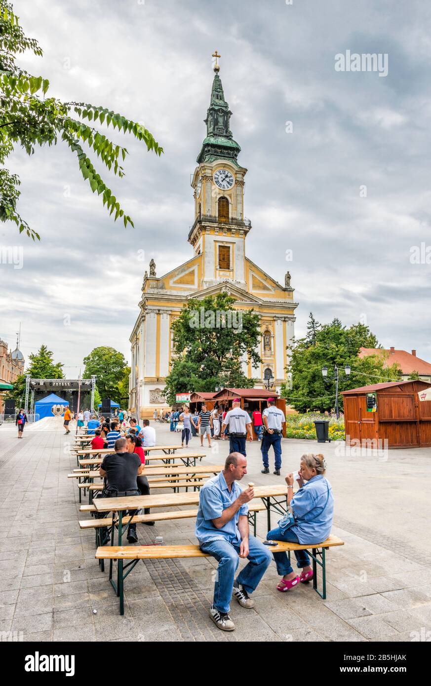 Menschen an Tischen im Freien am Kossuth-Platz, Große Kirche hinter, in Kecskemet, Südliche Große ungarische Tiefebene, Bacs-Kiskun-Kreis, Ungarn Stockfoto