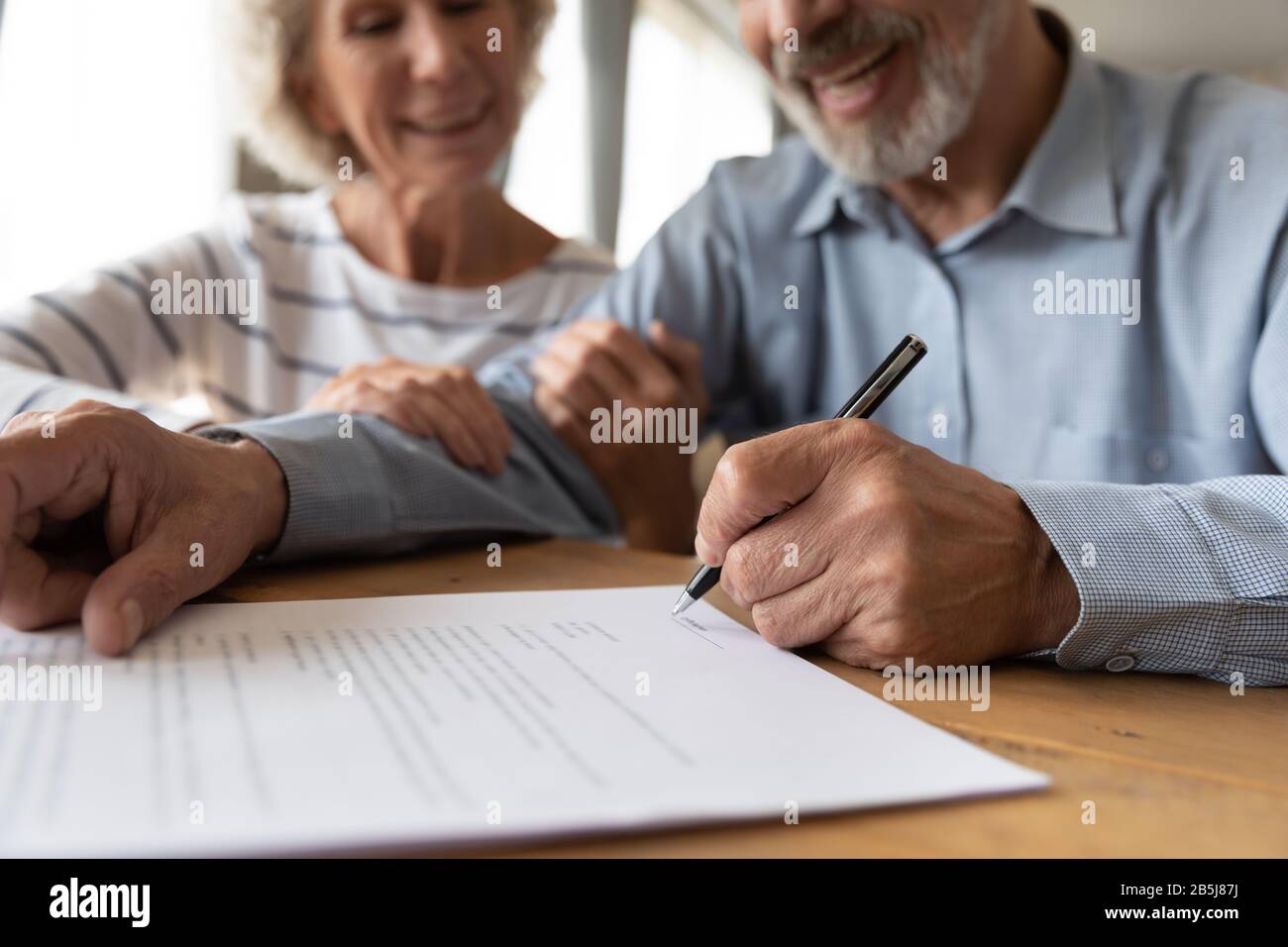 Altes Paar unterzeichnet Vertrag Stockfoto