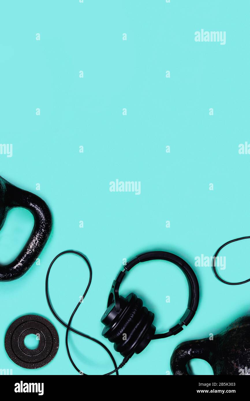 Vertikales Sportbild. Gewichte und Kopfhörer auf blauem Hintergrund. Flaches Layout, Draufsicht, Kopierbereich. Stockfoto