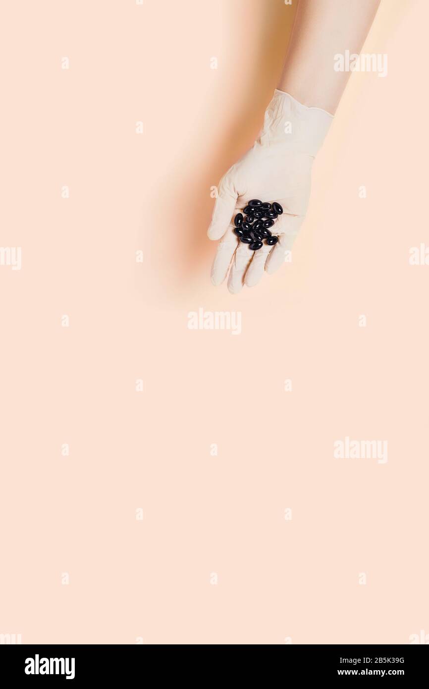 Hand in medizinischen Handschuh mit Tabletten auf pinkfarbenem Hintergrund. Flache Lage, Draufsicht. Stockfoto