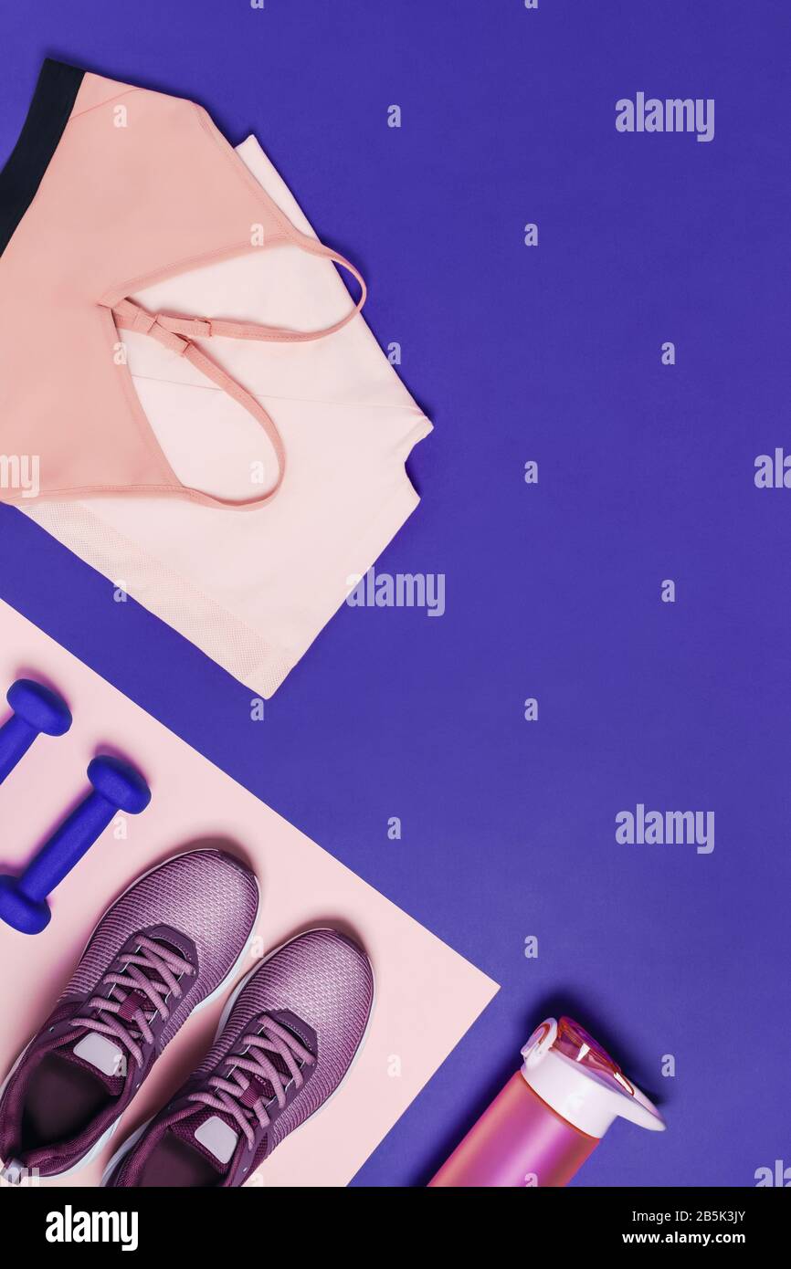 Sportgeräte für das Frauentraining. Rosa-blauer vertikaler Hintergrund, diagonale Zusammensetzung. Stockfoto