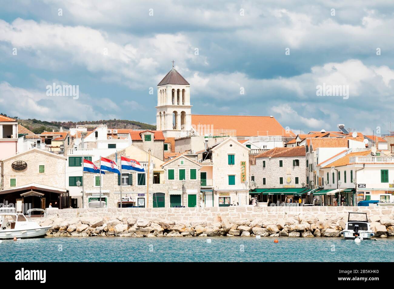 Vodice, Kroatien - 22. August 2017: Sonniger Morgen in der kleinen mediterranen Stadt mit Steinhäusern und altem Kirchturm. Mit Wasserboots auf der Außenseite Stockfoto Vodice, Kroatien - 22. August 2017: Sonniger Morgen in der kleinen mediterranen Stadt mit Steinhäusern und altem Kirchturm. Mit Wasserboots auf der Außenseite Stockfoto