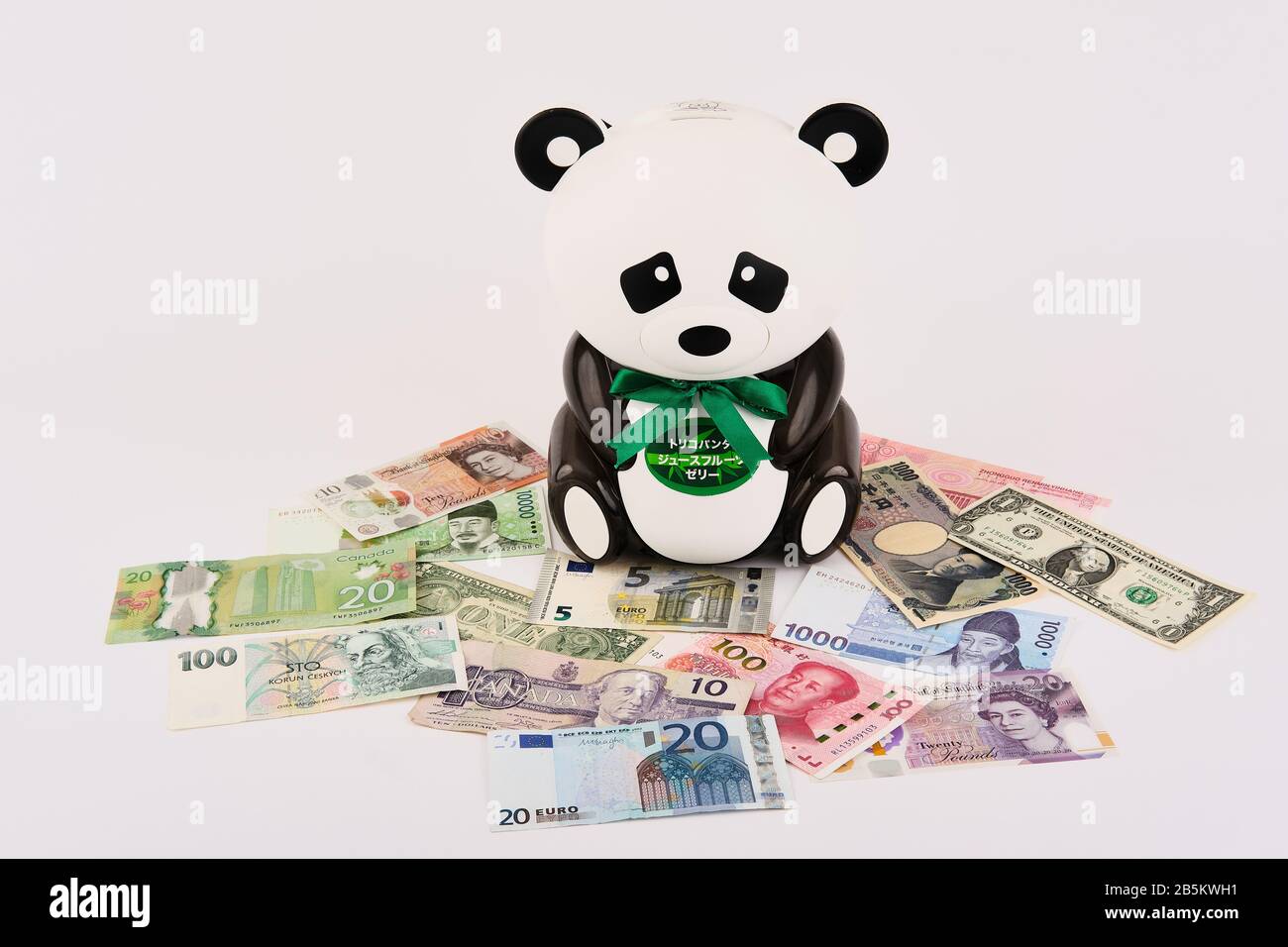 Panda Bear Piggy Bank umgeben von verschiedenen West- und Ostweltwährungen Stockfoto