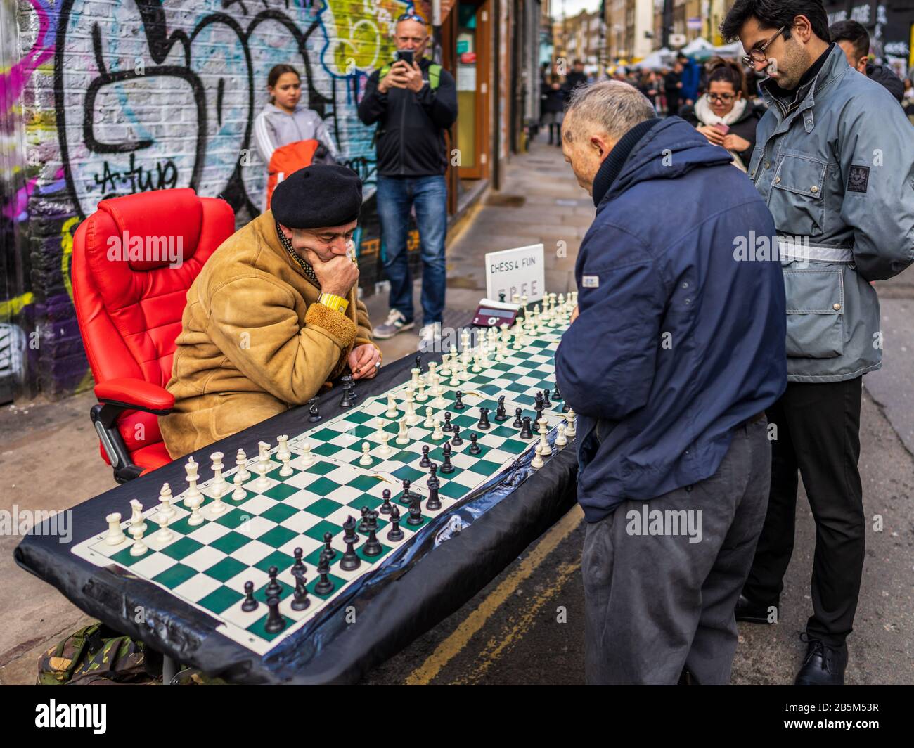 Brick Lane Schach - ein Schachspieler spielt bis zu 4 parallele Spiele mit Touristen und Passanten in die beliebten Londoner Brick Lane Markt am Sonntag Stockfoto