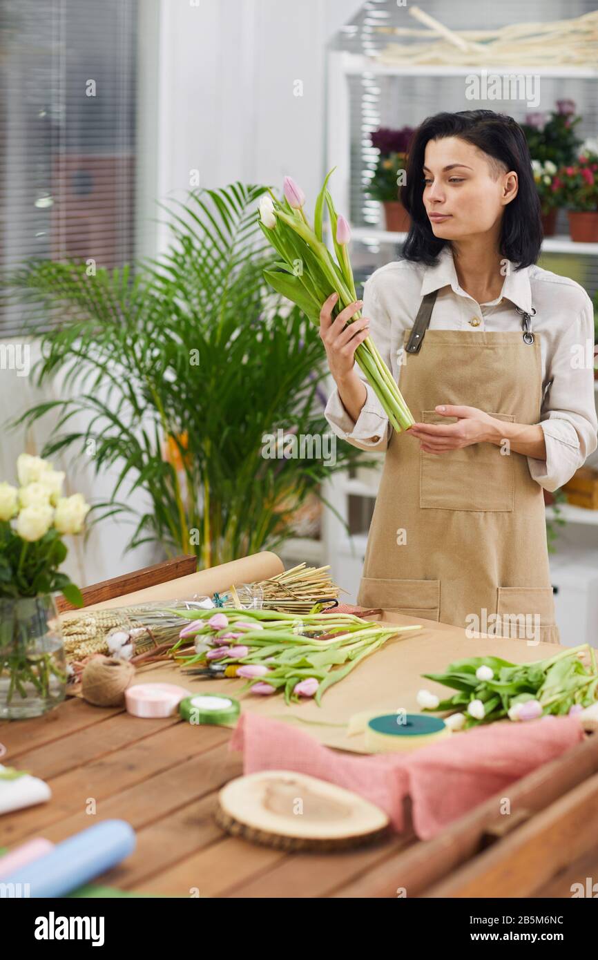 Portrait junger Blumenhändler, die während der Arbeit im Geschäft Blumenkompositionen und Blumenstrauß mit Frühlings-Tulpen arrangieren Stockfoto