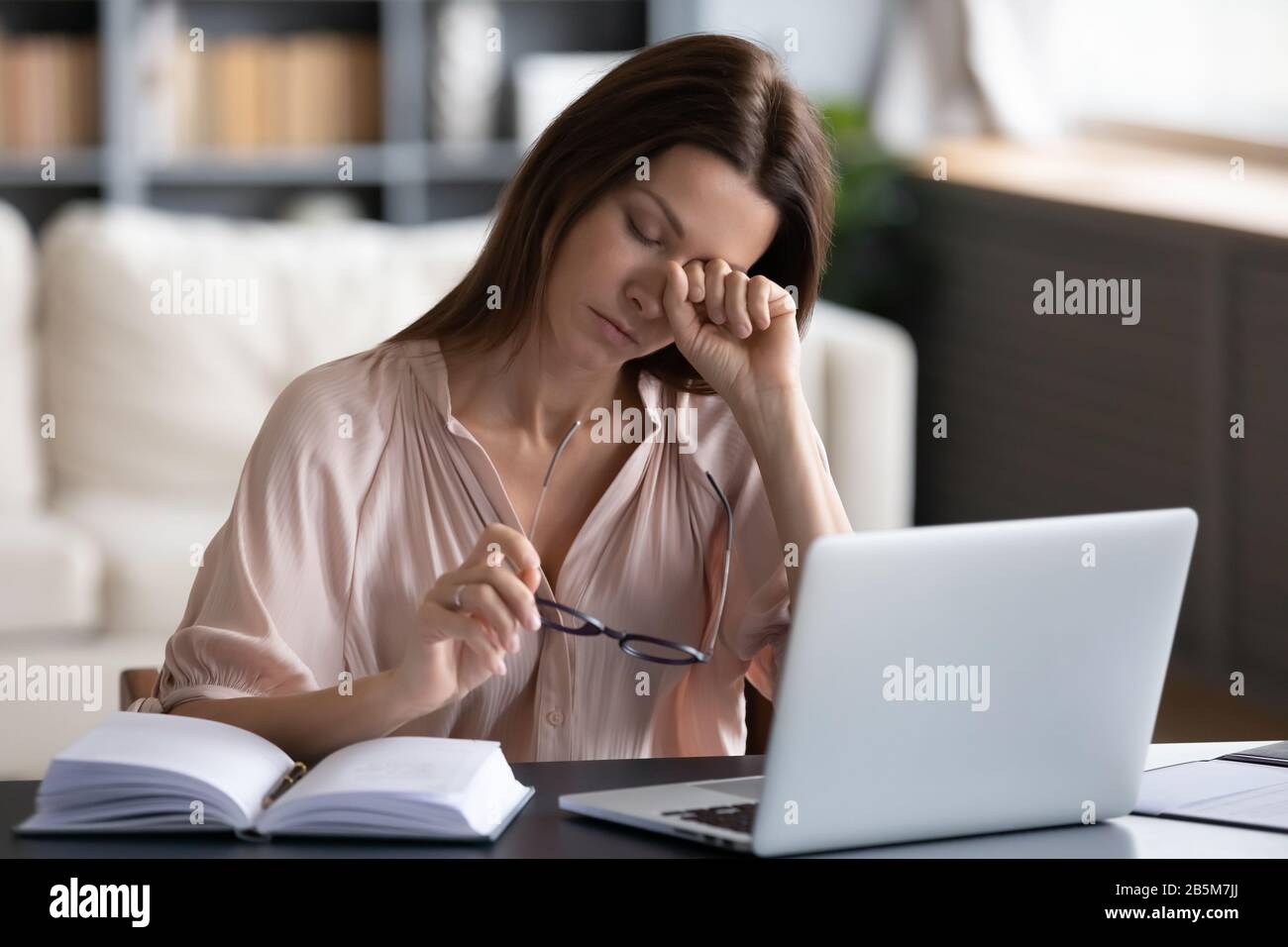 Müde gestresste Dame, die an einem trockenen Augensyndrom leidet. Stockfoto