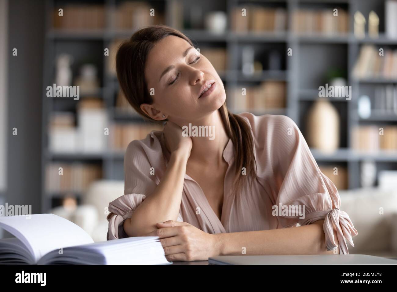 Junge gestresste Frau, die unter Nackenschmerzen leidet. Stockfoto
