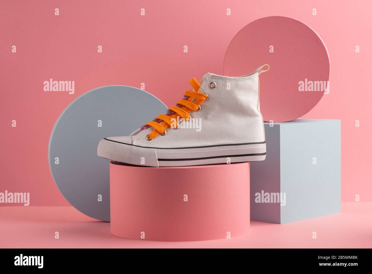 Sneaker auf pinkfarbenem Hintergrund mit bunten Zylindern und Würfel Stockfoto