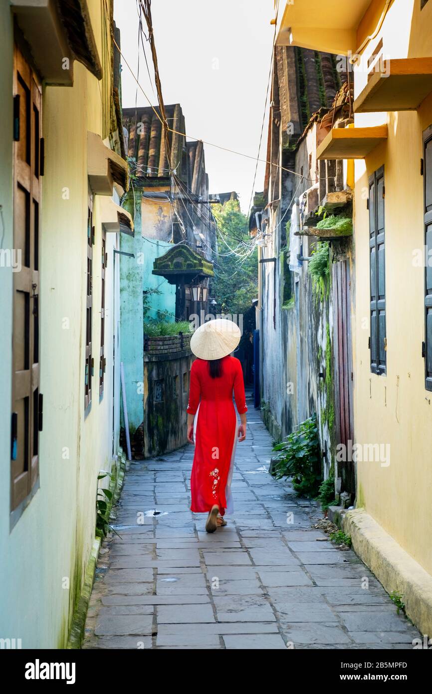 Eine junge Vietnamesin, die ein traditionelles Ao Dai Kleid in den Straßen von Hoi An, Vietnam trägt Stockfoto