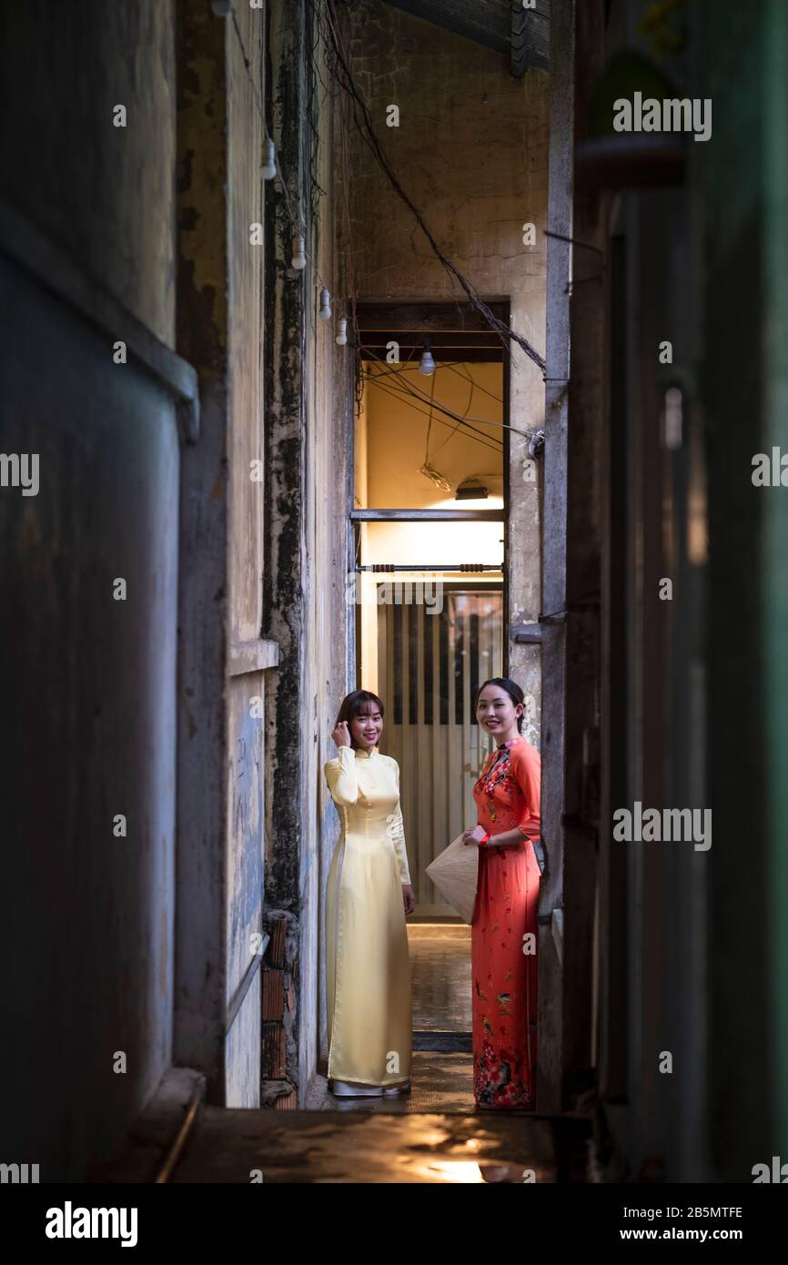 Zwei junge Frauen in Ao Dai kleiden sich in einem schlechten Wohnkomplex im alten Saigon, Vietnam Stockfoto