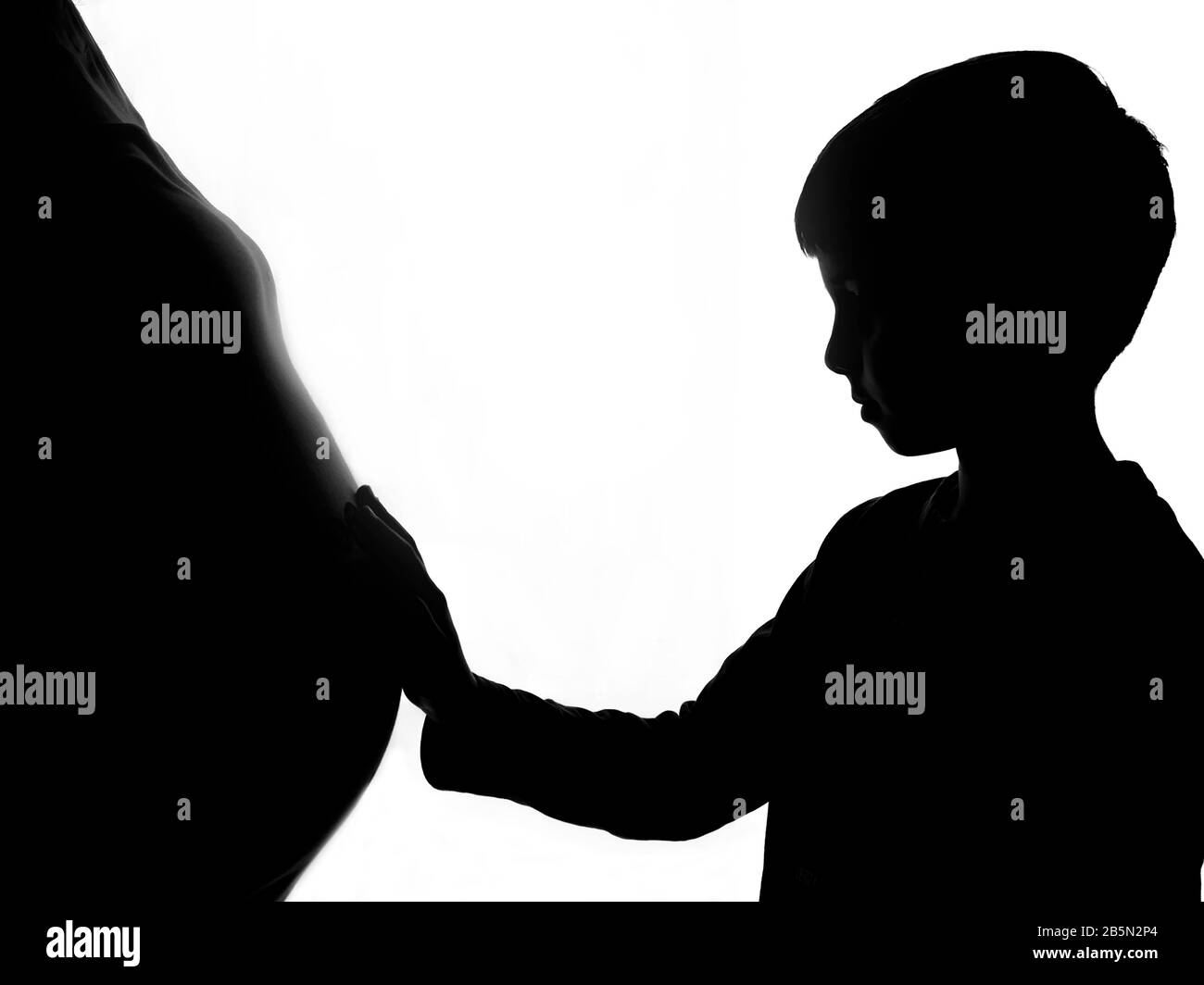 Silhouette eines jungen Jungen, der den Bauch seiner schwangeren Mutter berührt. Ein Geschwisterchen erwartet. Stockfoto