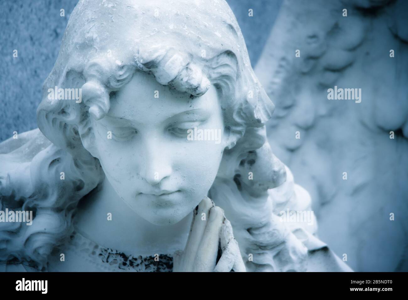 Wächter Engel Mädchen Skulptur Detail. Angel traurige Ausdrucksskulptur mit Augen nach unten und den Händen zusammen. Farbfoto mit Blautönen. Nicht moderne Religi Stockfoto