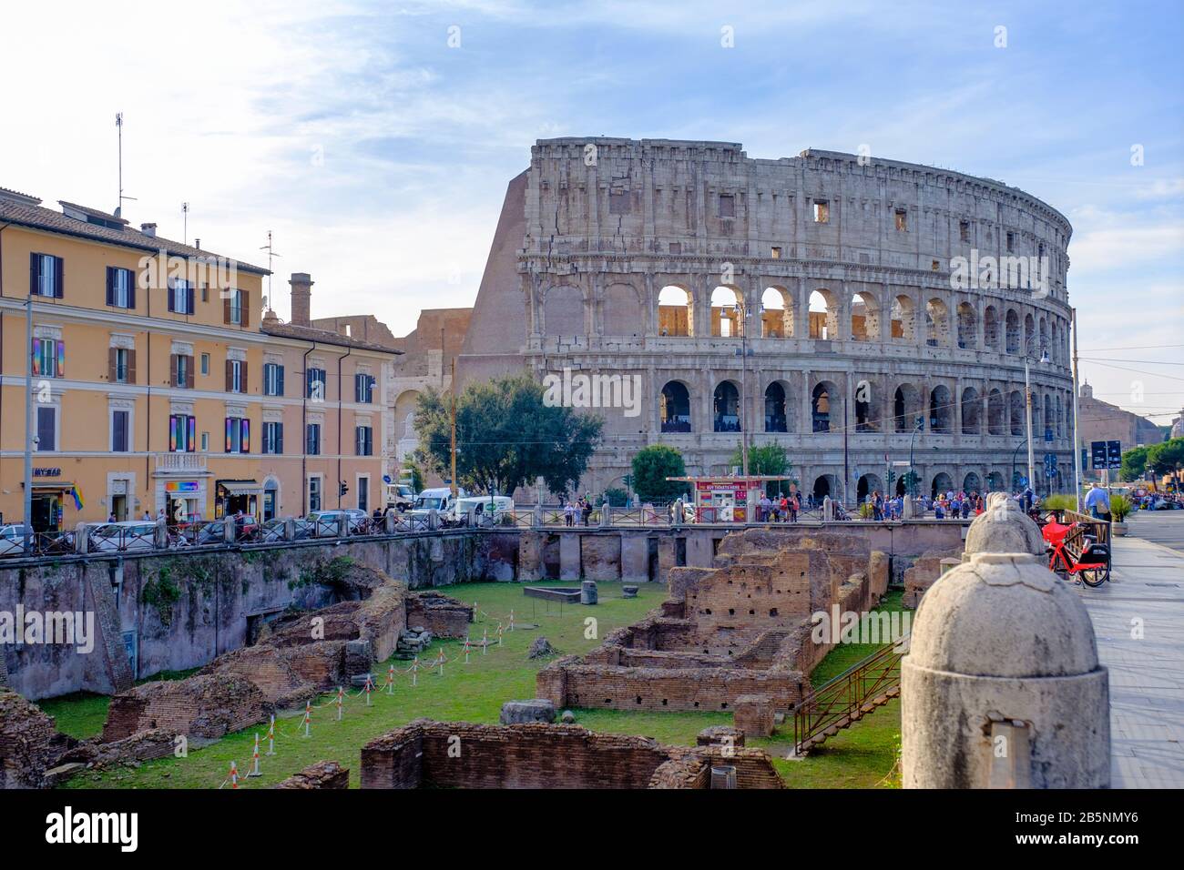 Antike Gebäude in Rom, Straßenblick auf die Ruinen von Ludus Magnus, große Gladiatorenschule, mit römischem Kolosseum im Hintergrund, Rom, Italien. Stockfoto