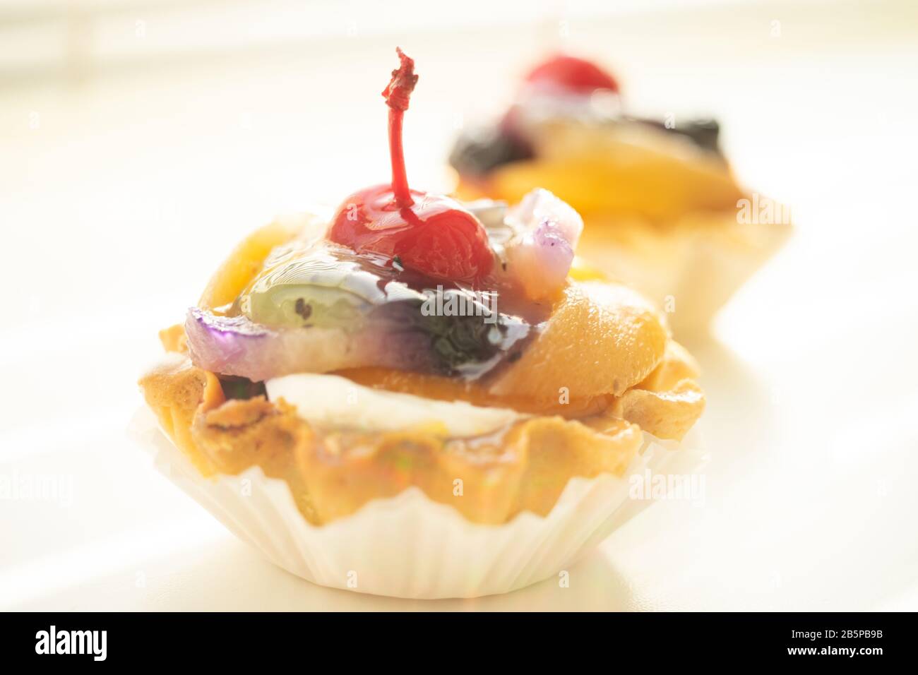 Kuchenkorb mit Früchten und Kirsche auf dem Tisch Stockfoto