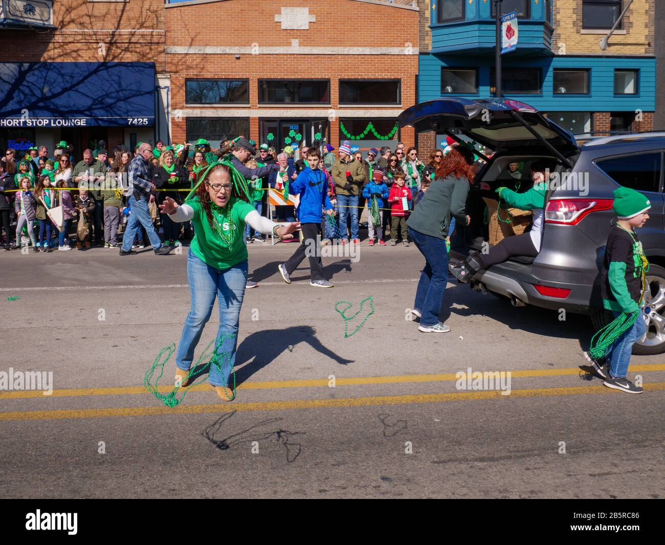 Forest Park, Illinois USA. März 2020. Während der heutigen Saint Patrick's Day Parade wirft eine Frau der Menge grüne Perlen. Stockfoto