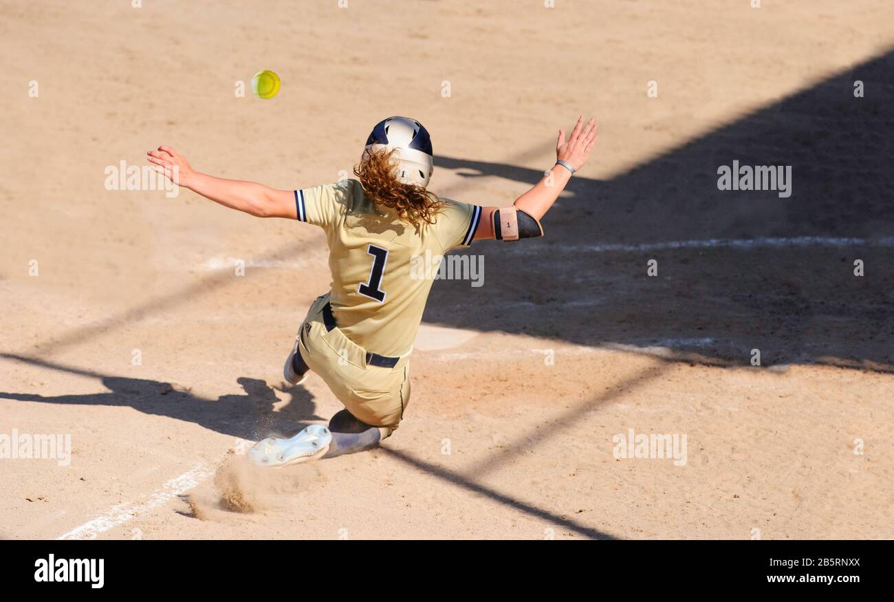 Ein Baseball-Spieler Schiebt Sich In die Home Base, Während der Ball Durch die Luft fliegt Stockfoto