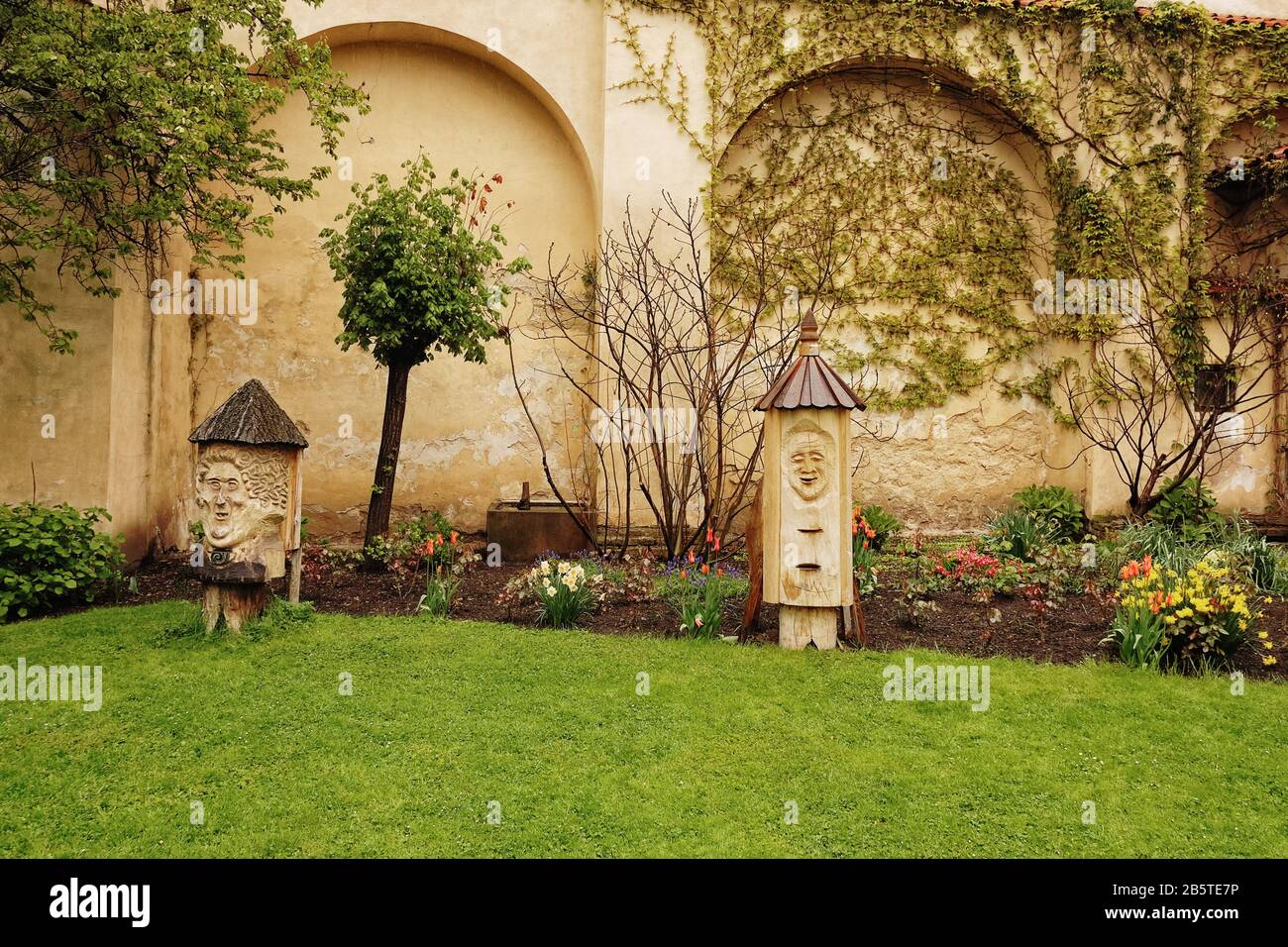 Geschnitzte Baumstumpf-Narben bewachen das Blumenbeet in den Vojan Gardens, einem ruhigen Stadtpark mit Pfauen Spazierwegen, grünen Rasenflächen, Gärten und Obstbäumen Stockfoto