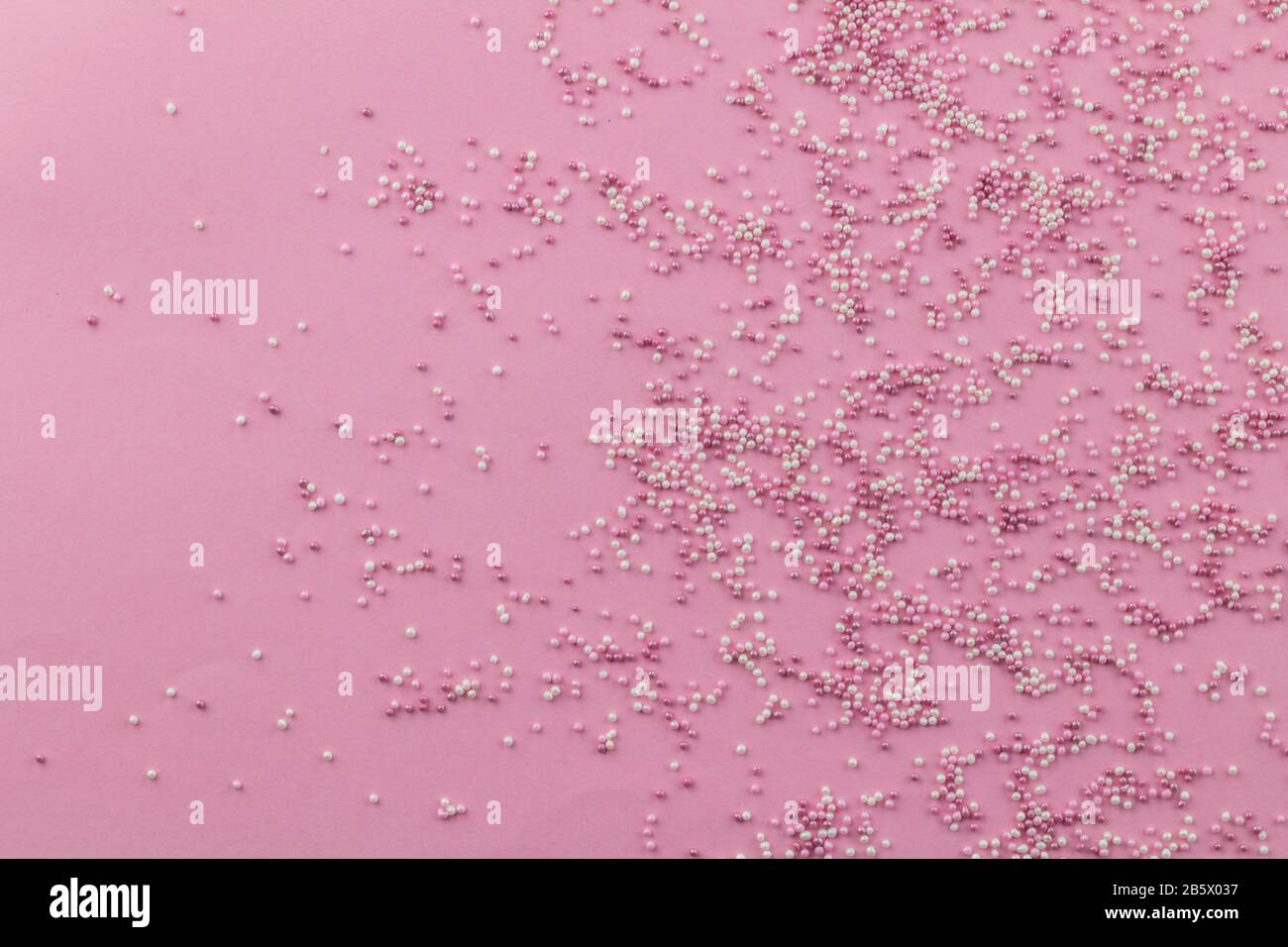 Streuen Sie den Hintergrund mit pinkfarbenen und weißen Kuchentürmchen, die auf blassrosa Hintergrund verstreut sind und Platz für Text haben - Draufsicht Stockfoto