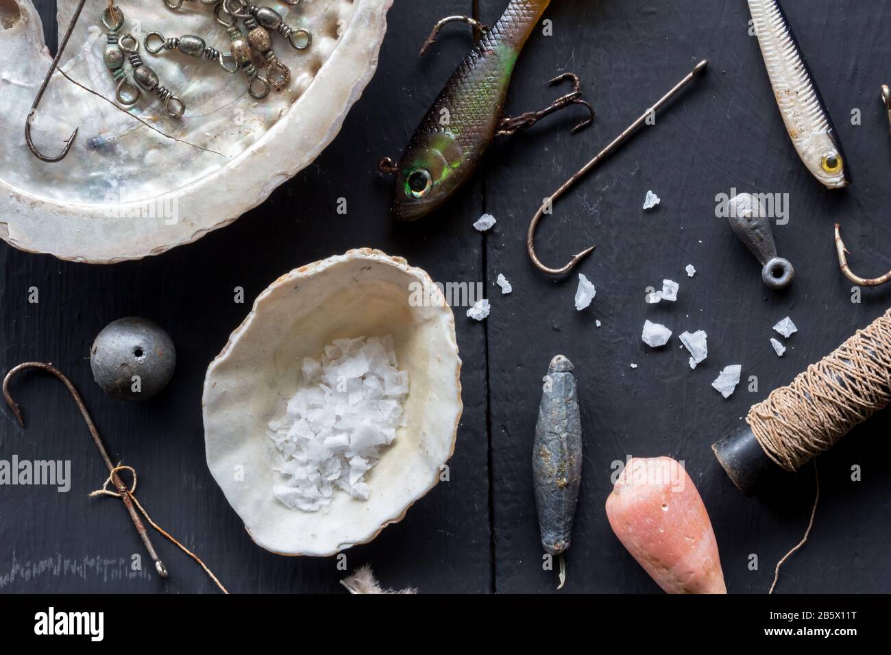 Verschiedene Angelhaken, Luren, Sinkkörper und Schalen, konzeptionelles Foto mit stlliger Lebensdauer über dem Kopf Stockfoto