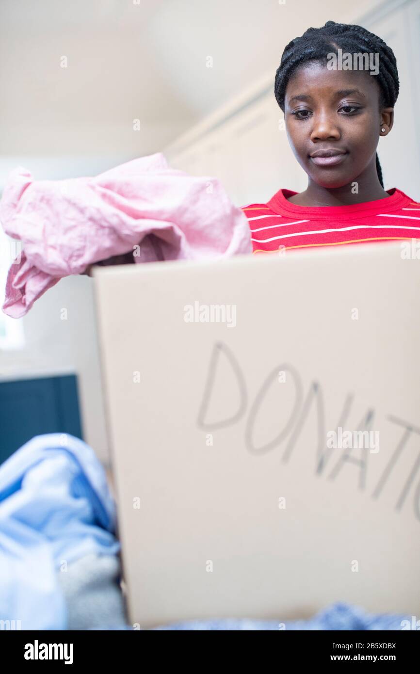 Teenager-Mädchen, Das Unerwünschte Kleidung In Box Für Die Charity Collection Einbringt Stockfoto