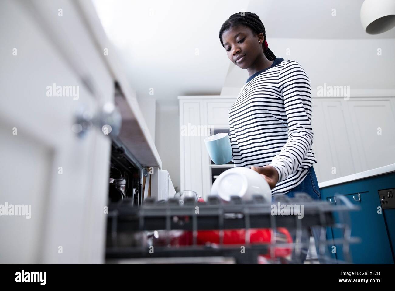 Teenage Girl Boy Helfend With Chores At Home By Stacking Crockery In Geschirrspüler Stockfoto