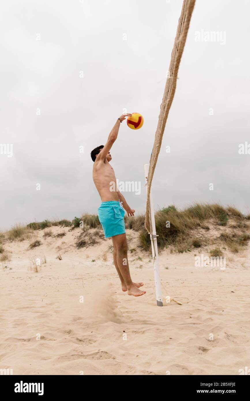 Junger Mann, der am Sommerstrand Volleyball spielt. Sport, Fitness und People Konzept Stockfoto