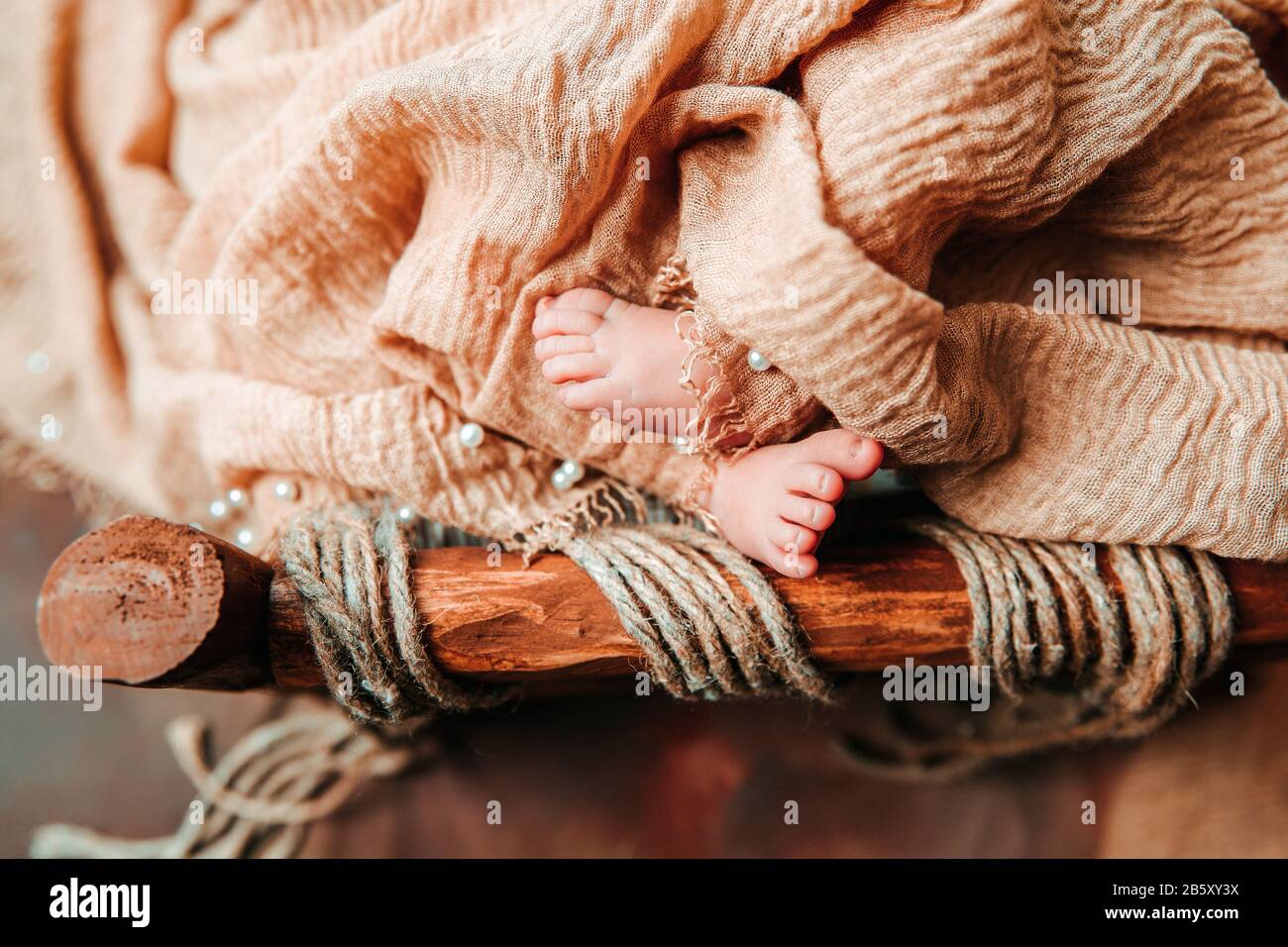 Ein neugeborenes, süßes Baby, das in einer alten Holzwiege mit offenem Fuß und Zehen schläft Stockfoto