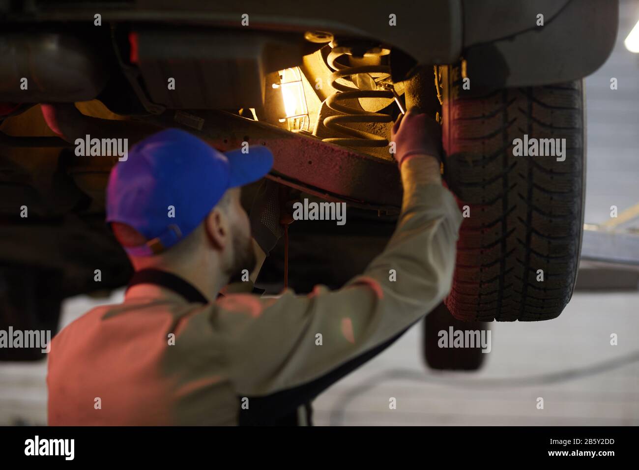 Horizontale Rückansicht Aufnahme von nicht erkennbarem Reparaturmann Befestigung Schraubenfeder undr Auto, horizontaler Schuss Stockfoto