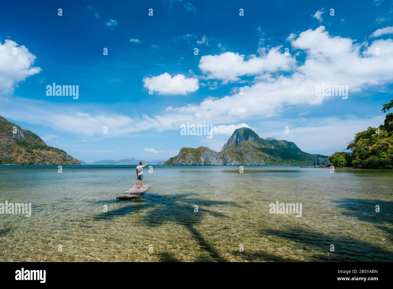 Man auf Bambus schwimmt in einer flachen Lagune mit Panoramablick auf die flache Lagune und die Inseln in der Cadlao-Bucht. Palawan, Philippinen. Urlaubsferienkonzept. Stockfoto