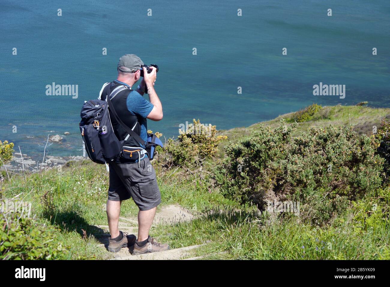 Mann Wanderer Fotos mit Kamera vom National Trusts Abbotsham Cliff in der Nähe von Westward Ho! Auf dem South West Coast Path, North Devon, Großbritannien. Stockfoto