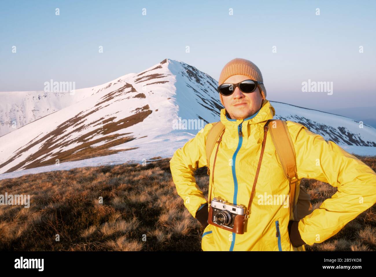 Fotograf in gelber Jacke unter Foto auf verschneite Feld Stockfoto