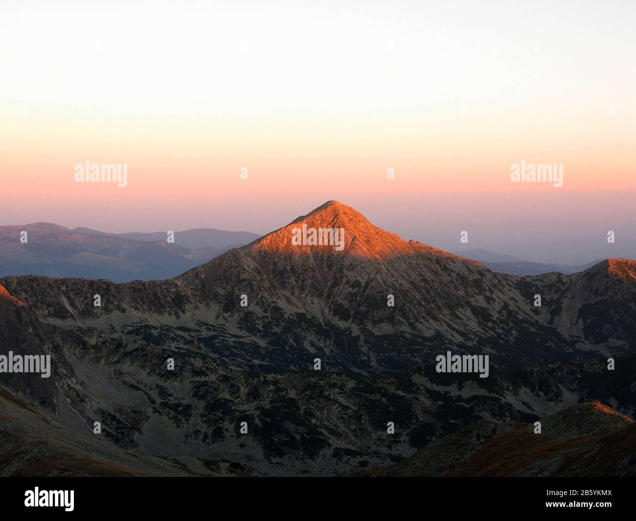 Sonnenaufgang über einem pyramidenförmigen Berggipfel im Spätsommer in den Südkarpaten Stockfoto