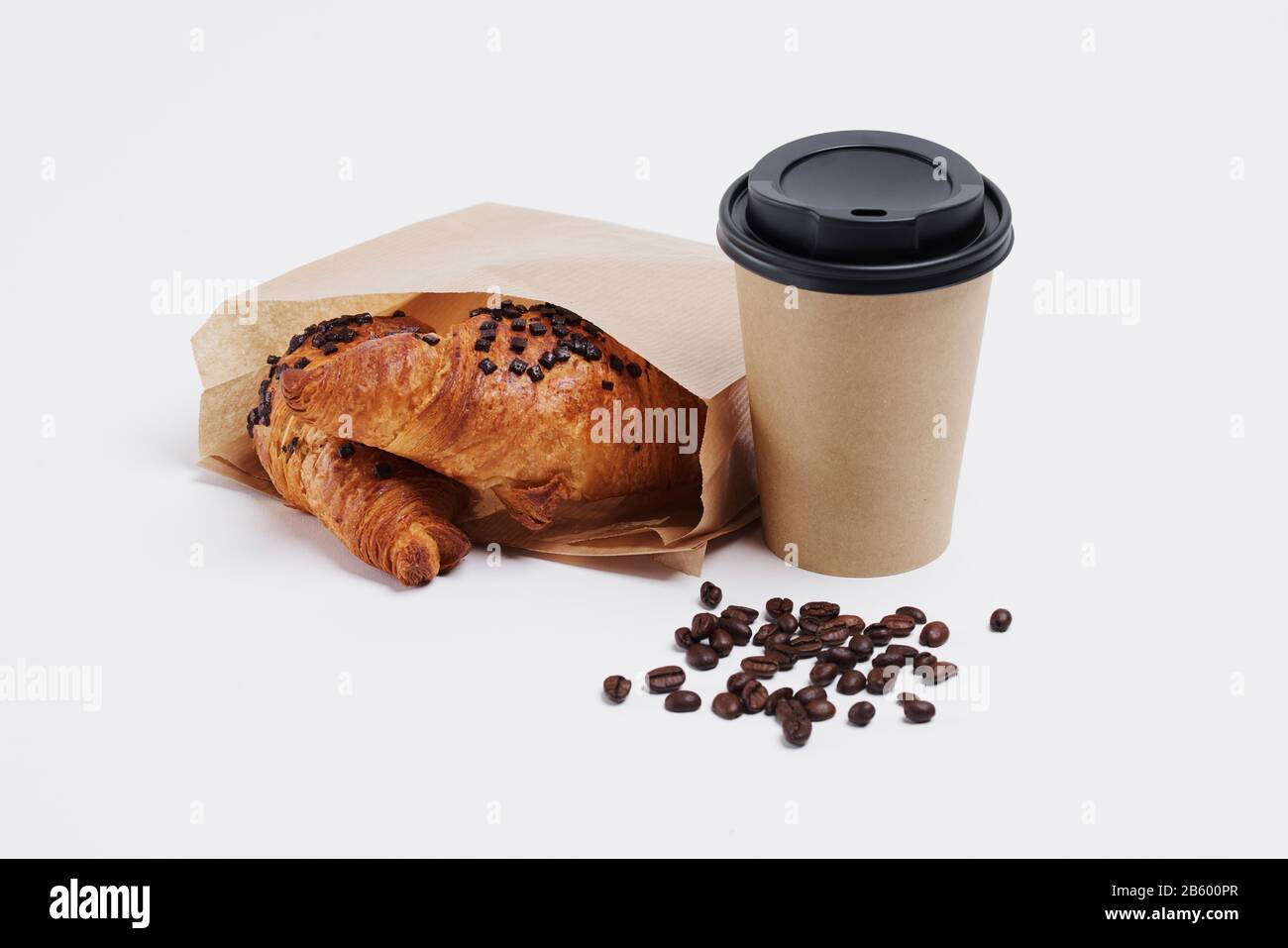 Einwegbecher mit heißem Kaffee und Croissant Stockfoto